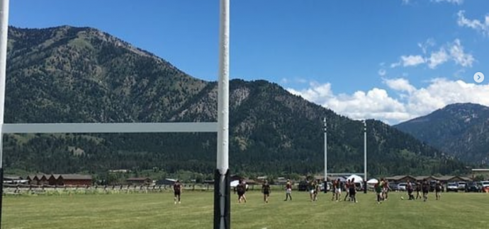 rugby field with players - rocky mountins in background